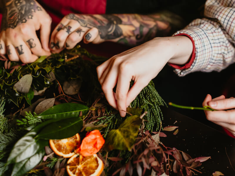 Two pairs of hands making a Christmas wreath